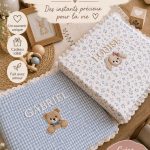 Livre de souvenirs personnalisé pour bébé avec broderie de nom, sur une table en bois.
