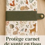 Protège carnet de santé en tissu coloré sur une table avec des fournitures de couture