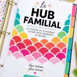 Un classeur de gestion familiale ouvert avec des onglets colorés et des notes.