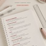 Un étudiant rédige des notes dans un cahier, entouré de livres.